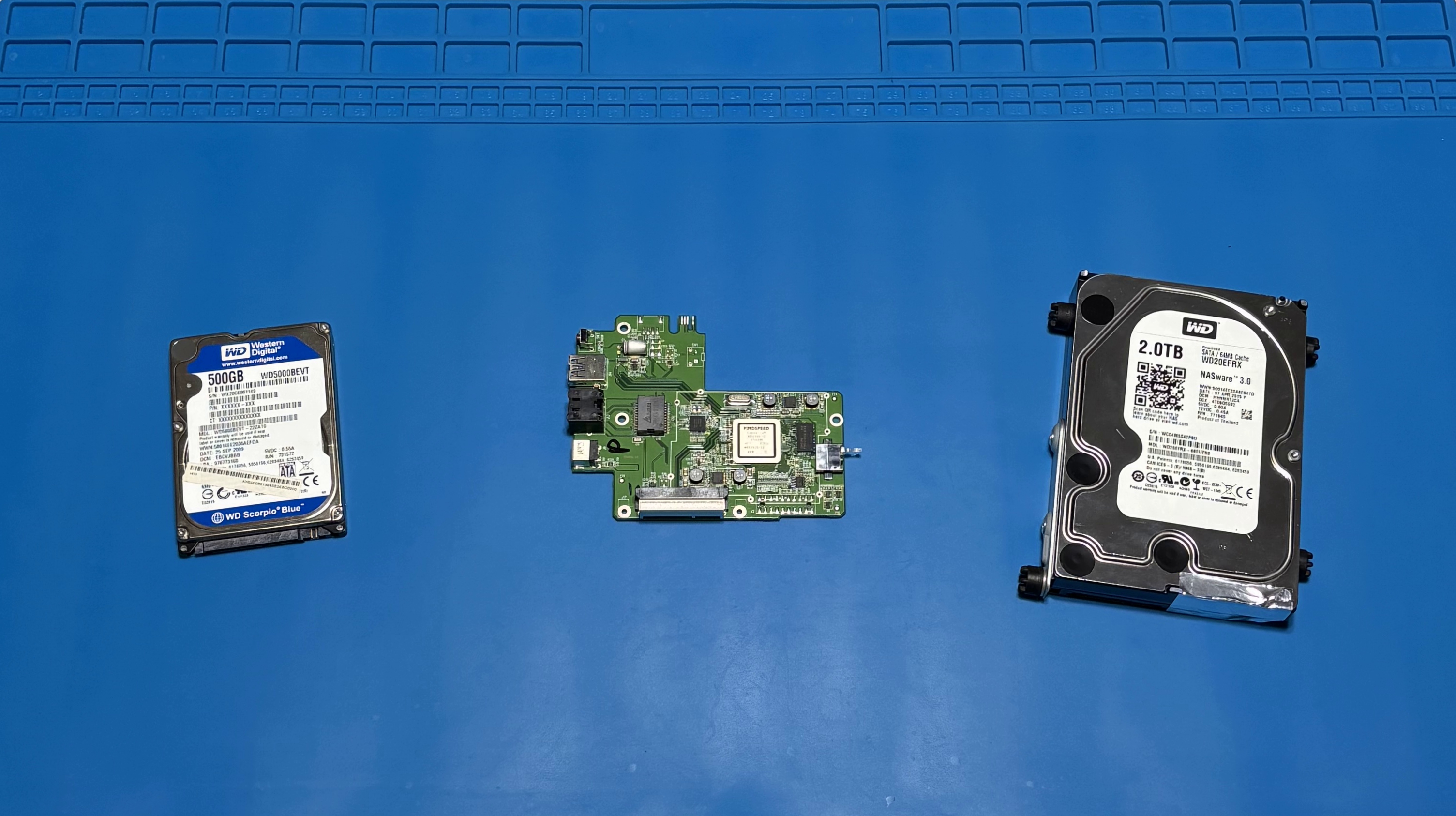 Festplatten und Elektronikplatine auf blauer Arbeitsmatte